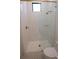 A stylish, all-white bathroom features glass enclosed shower with gold fixtures and mosaic tiled floor at 1220 Delaney Park Dr, Orlando, FL 32806