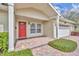 Inviting home entrance featuring a covered porch, red door, brick walkway and manicured bushes at 1329 Maury Rd, Orlando, FL 32804