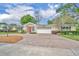 Charming single-story home with a red door, lush landscaping, and a spacious brick driveway at 1329 Maury Rd, Orlando, FL 32804