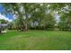 Spacious backyard with lush lawn and shade trees, offering a serene outdoor space for leisure and recreation at 1709 Iverness Ct, Longwood, FL 32779