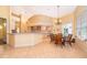 Bright kitchen with tile flooring, peninsula bar, and dining nook with a chandelier and large window at 1709 Iverness Ct, Longwood, FL 32779