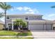 Charming two-story home featuring a three-car garage, well manicured lawn and mature palm trees at 1712 Boat Launch Rd, Kissimmee, FL 34746