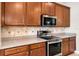 Well-equipped kitchen featuring stainless steel appliances, granite countertops, and wood cabinets at 1712 Boat Launch Rd, Kissimmee, FL 34746