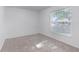 Cozy bedroom with neutral carpet, window overlooking the outdoors, and fresh white walls at 205 Lori Ct, Umatilla, FL 32784