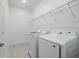Well-lit laundry room features modern washer and dryer with convenient shelving at 2152 Rock Maple Bnd, Kissimmee, FL 34746