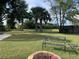 Spacious backyard with lush lawn, mature trees, a brick fire pit, and comfortable bench seating at 2155 Palm View Dr, Apopka, FL 32712
