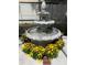 Close-up of a decorative three-tiered water fountain surrounded by colorful flowers at 2155 Palm View Dr, Apopka, FL 32712