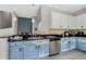 Well-lit kitchen with stainless steel appliances, black countertops, and blue lower cabinets at 2256 Betsy Ross Ln, St Cloud, FL 34769