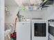Bright laundry room features a white washer and dryer with storage shelves at 2256 Betsy Ross Ln, St Cloud, FL 34769