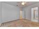 Bright bedroom with neutral carpet, ceiling fan, and white walls, leading to hallway and closet at 2311 Victoria Dr, Davenport, FL 33837