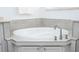 Close up on soaking tub with light stone surround and gray cabinets at 2602 Shirehall Ln, Winter Garden, FL 34787