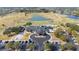Aerial view showcasing a clubhouse with a parking lot and surrounding golf course with lakes and lush landscaping at 2602 Shirehall Ln, Winter Garden, FL 34787