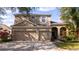 Tan two-story home with a two car garage and driveway and manicured landscaping at 2602 Shirehall Ln, Winter Garden, FL 34787