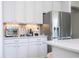 Close-up of a kitchen area showcasing stainless steel appliances, modern white cabinets, and sleek marble countertops at 2602 Shirehall Ln, Winter Garden, FL 34787