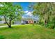Landscaped front yard featuring a grey garage door, red door, stone facade, and well-maintained lawn at 275 W 3Rd St, Chuluota, FL 32766