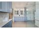 Elegant bathroom features blue cabinets, double sinks, quartz countertop, walk-in shower and access to the closet at 3281 Saloman Ln, Clermont, FL 34711