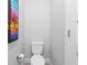A compact toilet with a modern design is situated next to a vibrant palm tree artwork at 34 Jackson Cir, Winter Springs, FL 32708