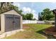Backyard featuring a shed, large lawn area, white fence, mature trees, and disc golf basket at 3511 E Crystal Lake Ave, Orlando, FL 32806