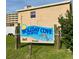 Holiday Cove North rental sign with dolphin against a tan building with nice grass at 573 N Atlantic Ave # 5, New Smyrna Beach, FL 32169