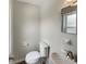 Bright bathroom featuring white toilet, sink, and mirror, with neutral-toned walls and flooring at 6740 Se 107Th St, Belleview, FL 34420
