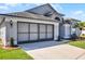 View of the property's two car garage, lawn and partial view of the home at 7606 Fordham Creek Ln, Orlando, FL 32818