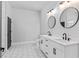 Modern bathroom featuring double vanity with white cabinetry, black hardware, round mirrors, and hexagon tile floors at 8003 Lake Nellie Rd, Clermont, FL 34714