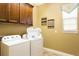 Functional laundry room featuring a washer, dryer, overhead cabinets, and a bright window at 834 Golden Bear Dr, Reunion, FL 34747