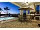 Outdoor entertaining space with a grill, an umbrella-covered table, and a pool at twilight at 834 Golden Bear Dr, Reunion, FL 34747