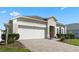 Charming single-story home featuring a well-manicured lawn, brick driveway, and a two-car garage at 838 Kildrummy Dr, Davenport, FL 33896