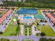 An aerial view showcases the pool, tennis courts, green spaces, lake, and overall community layout at 8971 California Palm Rd, Kissimmee, FL 34747
