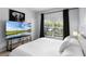 Light-filled bedroom with neutral decor, a mounted TV, and a view of greenery outside the window at 8971 California Palm Rd, Kissimmee, FL 34747