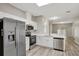 Open kitchen with stainless steel appliances, white cabinets, countertop seating, and modern flooring at 9999 Shadow Creek Dr, Orlando, FL 32832