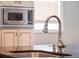 Close up of the kitchen island sink, faucet, and cabinets. Also includes a view of an installed microwave at 1209 Gunnison Ave, Orlando, FL 32804