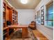 Well-lit office features custom bookshelves, hardwood floors, large windows, and a classic chair providing an ideal workspace at 1209 Gunnison Ave, Orlando, FL 32804
