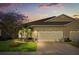 Charming single-story home with a well-maintained lawn and a two-car garage at dusk at 122 Lower Lake Ct, Debary, FL 32713