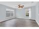 Spacious living room with modern gray floors, a ceiling fan, and ample natural light from the windows at 13118 Honey Locust Dr, Orlando, FL 32828