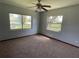 Bright bedroom with neutral walls, plush carpeting, and natural light from two windows with peaceful neighborhood views at 1312 Simmons Rd, Kissimmee, FL 34744