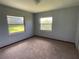 Inviting bedroom featuring neutral walls, plush carpeting, and natural light from two windows with pleasant outdoor views at 1312 Simmons Rd, Kissimmee, FL 34744