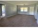 Spacious living room featuring neutral walls, plush carpeting, and natural light through a large window at 1312 Simmons Rd, Kissimmee, FL 34744