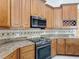 A kitchen features custom wood cabinetry, granite countertops, tile backsplash, and a black stove at 13139 Paloma Dr, Orlando, FL 32837