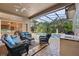 Covered patio features comfortable seating, outdoor kitchen, and serene pool view at 1544 Hunters Mill Pl, Oviedo, FL 32765