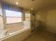 Bright bathroom featuring a soaking tub next to a window, and a glass shower at 2840 Roccella Ct, Kissimmee, FL 34747