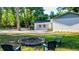 Backyard with a brick fire pit and chairs surrounded by lush green trees, creating a cozy outdoor space at 30542 Hoylake St, Sorrento, FL 32776