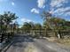 Scenic view of the property entrance with a decorative gate, mature trees, and a black wooden fence at 32325 State Road 44, Eustis, FL 32736