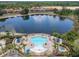Aerial view of community pool, lake, and homes with red tile roofs surrounded by lush landscape at 330 Rosso Dr, Davenport, FL 33837