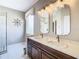 Well-lit bathroom featuring double vanity, marble countertop, and a glass-enclosed shower for a spa-like experience at 330 Rosso Dr, Davenport, FL 33837