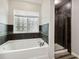 Bright bathroom features a soaking tub, decorative tile accents, and a glass-enclosed shower at 350 Black Springs Ln, Winter Garden, FL 34787