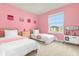 Charming pink bedroom with twin beds, a dresser, and plenty of natural light at 3838 Lana Ave, Davenport, FL 33897