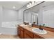 A well-lit bathroom featuring double sinks, a large mirror, and a soaking tub at 408 Magpie Ct, Kissimmee, FL 34759