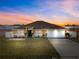 Charming home featuring a well-manicured lawn, two-car garage, and inviting curb appeal beneath a vibrant sunset sky at 408 Magpie Ct, Kissimmee, FL 34759